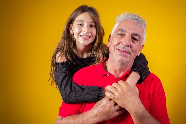 Bella bambina con suo padre più anziano su sfondo giallo. Festa del papà