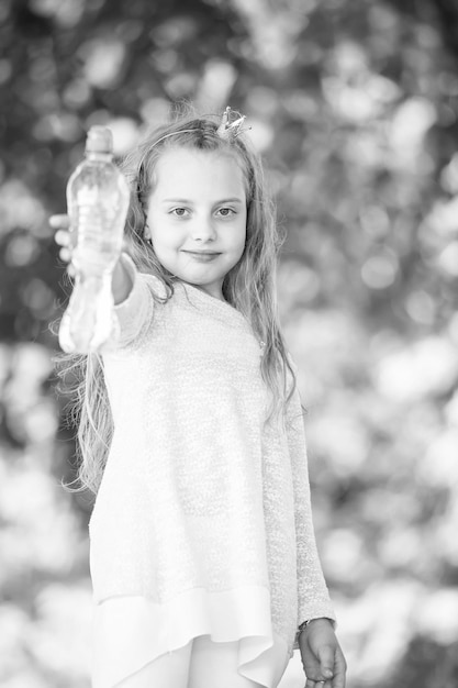 Bella bambina felice che beve acqua al giorno d'estate