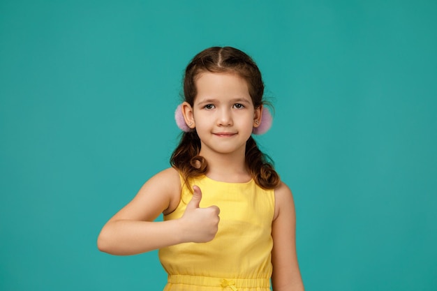 Bella bambina felice in abito che mostra i pollici in su