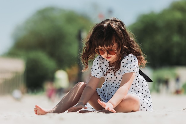 bella bambina in abito bianco che gioca sulla spiaggia