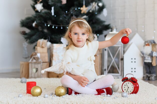 Bella bambina in attesa di un miracolo nelle decorazioni natalizie