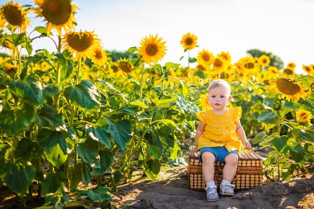 Bella bambina in un campo di girasoli in fiore in estate