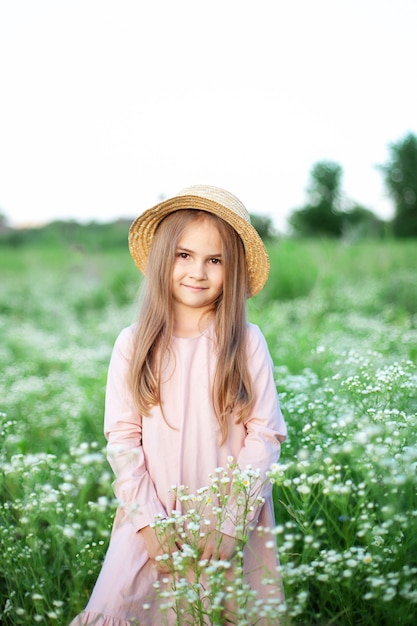 Bella bambina in un cappello di paglia e vestito