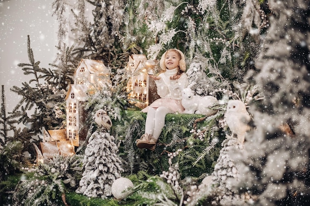 Bella bambina si rilassa con una decorazione natalizia con alberi e un piccolo coniglio bianco