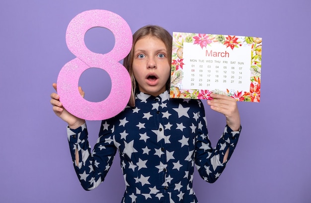 Bella bambina spaventata sulla felice festa della donna che tiene il calendario con il numero otto intorno al viso