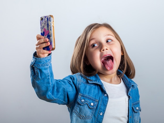 Bella bambina sta facendo selfie utilizzando uno smart phone