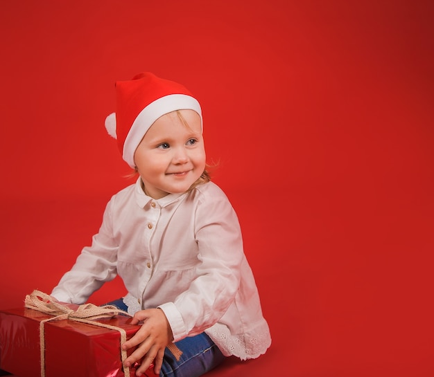 bella bambina su uno sfondo rosso con un cappello di Capodanno