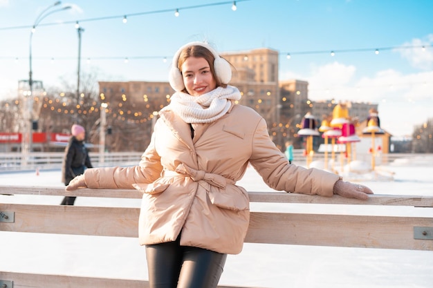 Bella bella giovane donna adulta brunet capelli caldi giacche invernali si trova vicino alla pista di pattinaggio su ghiaccio sfondo Town Square Christmas mood lifestyle