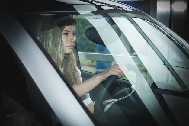 Bella bionda che guida un'auto, impara a guidare un'auto per ragazze, scuola guida.