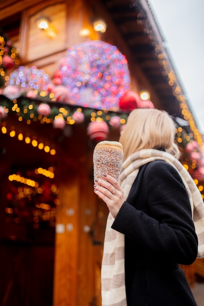 Bella bionda con la torta allo spiedo al mercatino di Natale a Wroclaw, Polonia