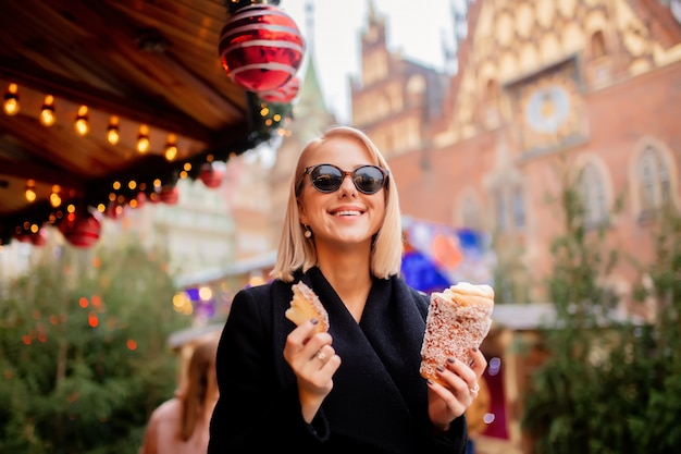 Bella bionda con la torta allo spiedo al mercatino di Natale a Wroclaw, Polonia