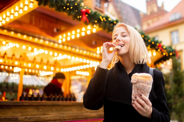 Bella bionda con la torta allo spiedo al mercatino di Natale a Wroclaw, Polonia