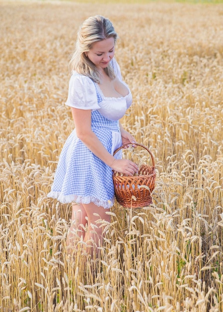 Bella bionda con un cesto strappa il grano nel campo