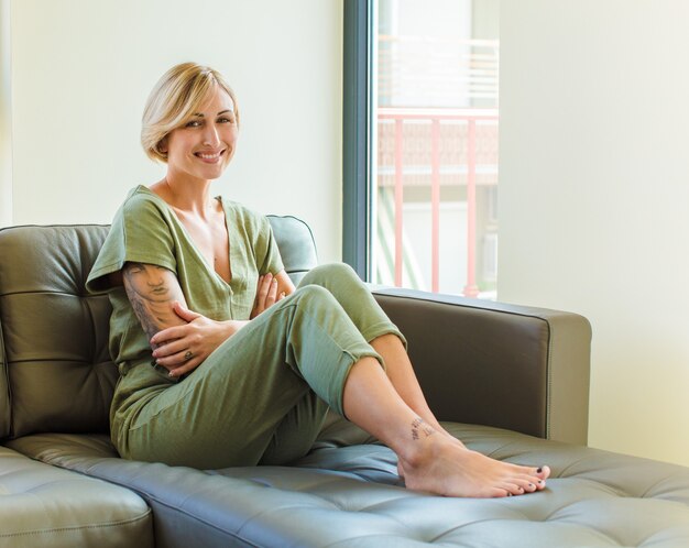 Bella bionda donna sorridente con le braccia incrociate e un'espressione felice, fiduciosa, soddisfatta, vista laterale