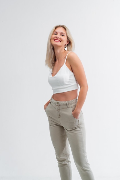 Bella bionda in jeans in studio su sfondo chiaro.