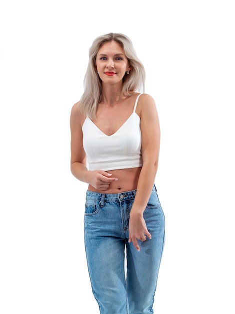 Bella bionda in jeans in studio su sfondo chiaro.