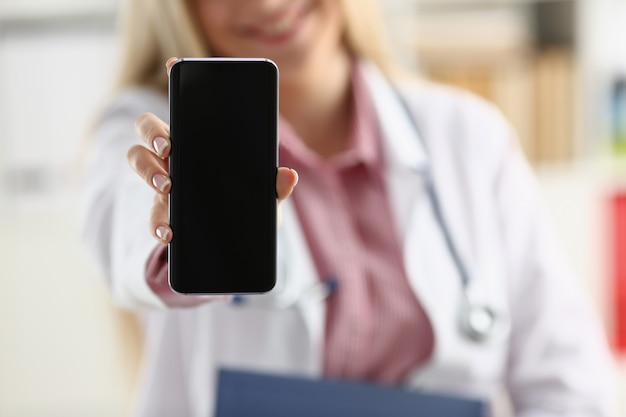Bella bionda medico femminile che tiene smartphone