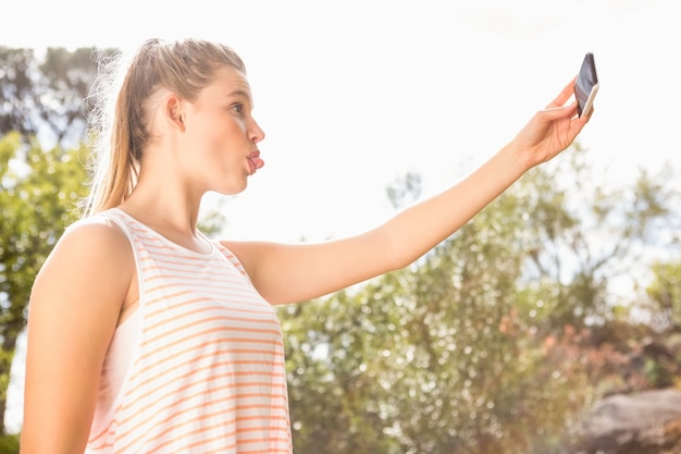 Bella bionda prendendo selfie con la lingua tesa