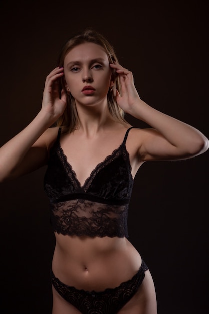 Bella, bionda sexy in biancheria intima di pizzo nero su una superficie scura