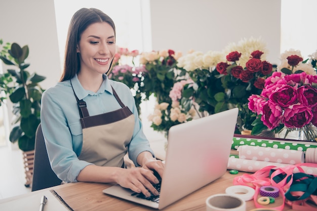 bella bruna botanica in posa nel suo negozio di fiori con il computer portatile