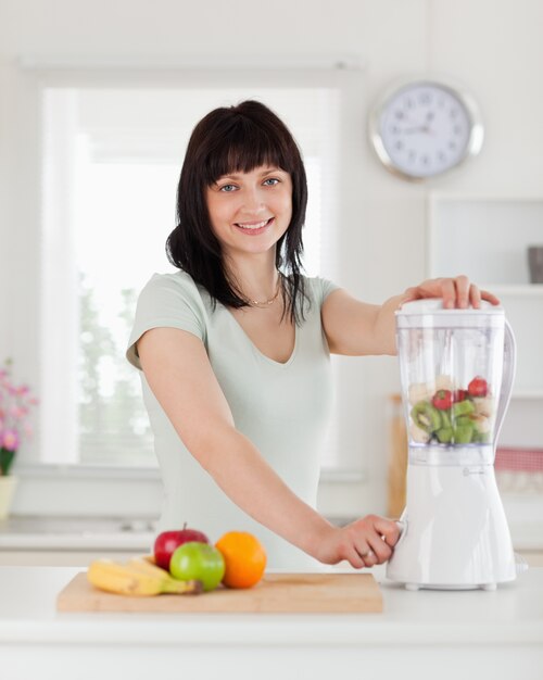 Bella bruna femmina utilizzando un mixer in piedi