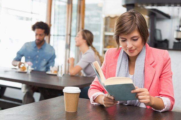 Bella bruna godendo il suo caffè con un libro