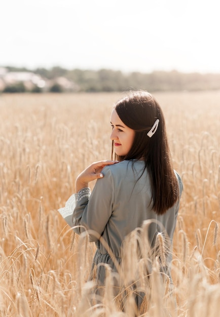 Bella bruna in piedi in un campo di grano