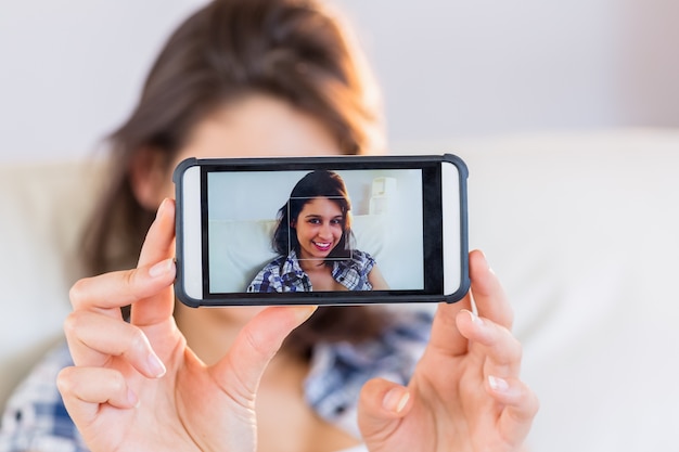 Bella bruna prendendo un selfie sul divano