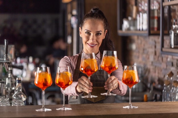 Bella cameriera che offre bicchieri di cocktail aperol spritz appena fatto.