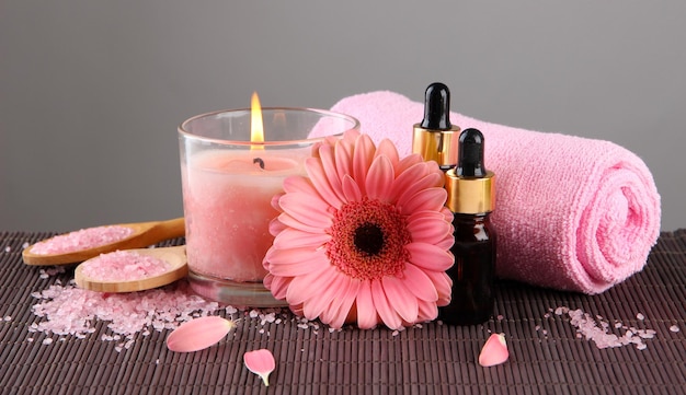 Bella candela rosa con fiori e asciugamano sulla stuoia di bambù