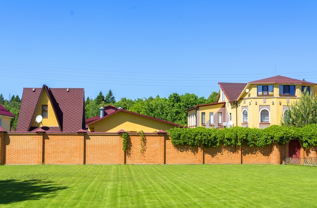 Bella casa di campagna con garage dietro una recinzione di mattoni.