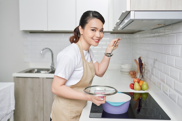 Bella casalinga che cucina con il mestolo in cucina