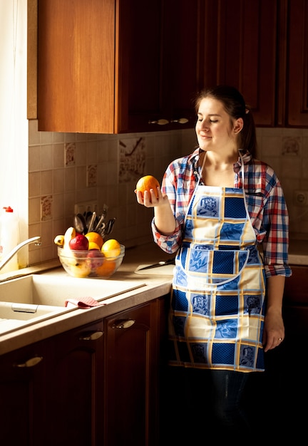 Bella casalinga che guarda l'arancia su una cucina in stile country