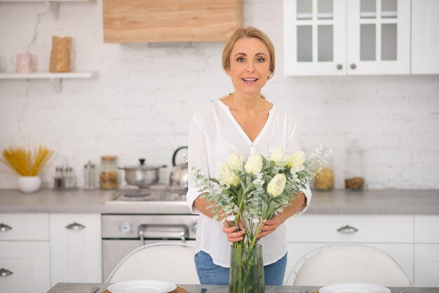 Bella casalinga che mette i fiori nel vaso