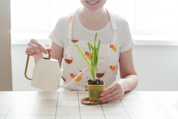 Bella casalinga donna in grembiule con fiore in vaso giardinaggio vacanze primavera e concetto di pasqua