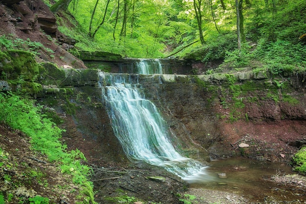 Bella cascata di foresta pluviale di montagna con acqua che scorre veloce e rocce a lunga esposizione Sfondo naturale per viaggi stagionali all'aperto in stile vintage hipster