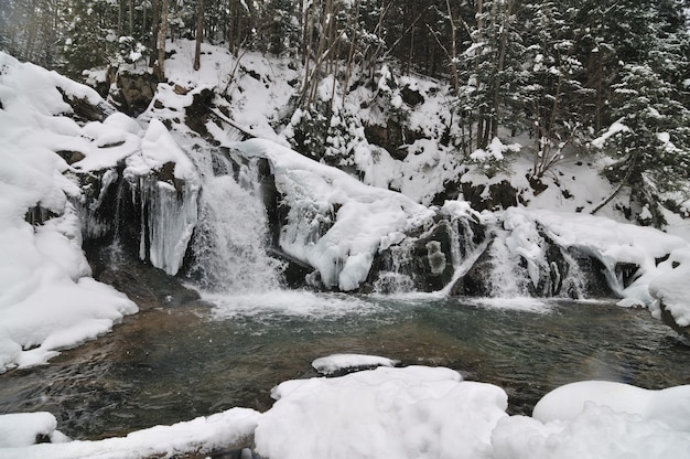 Bella cascata innevata che scorre in montagna