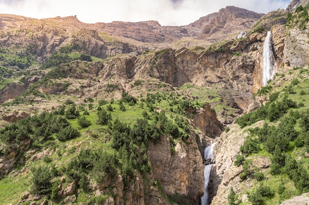 Bella cascata nel paesaggio delle montagne durante il tramonto