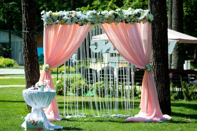 Bella cerimonia di matrimonio all'aperto Arco di nozze fatto di stoffa e fiori bianchi e rosa su uno sfondo di ristorante