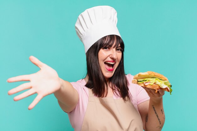 bella chef donna espressione sorpresa e con in mano un panino