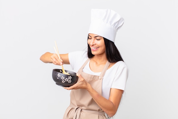 Bella chef ispanica che tiene in mano una ciotola di noodles