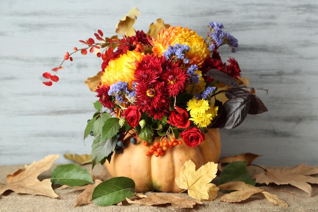 Bella composizione autunnale in zucca con foglie secche su sfondo di legno