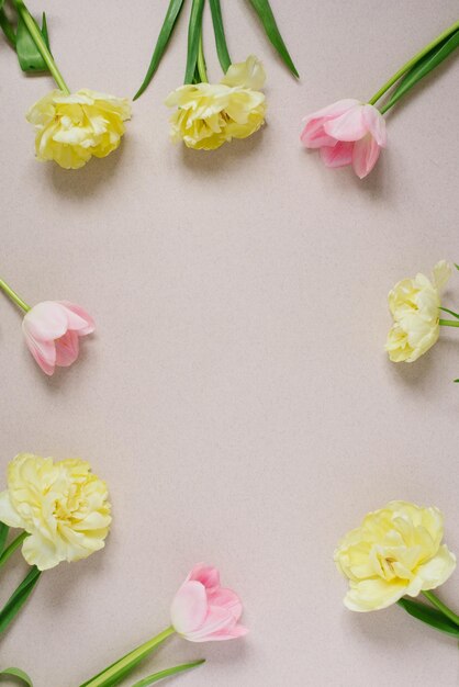 Bella composizione cornice di fiori primaverili Bouquet di tulipani rosa e gialli su un beige pastello