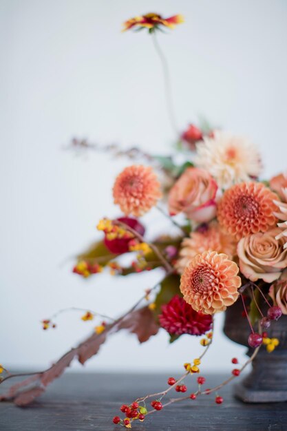 Bella composizione floreale con fiori e bacche arancioni e rossi autunnali Bouquet autunnale in vaso vintage su sfondo bianco