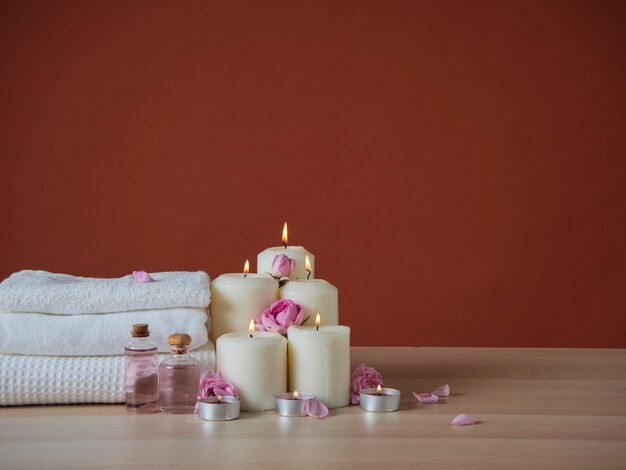 Bella composizione spa con candele profumate accese e olio aromatico, rose rosa sul tavolo di legno