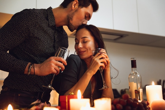 Bella coppia appassionata avente una romantica cena a lume di candela a casa, baci