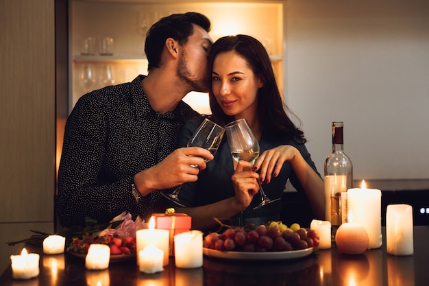 Bella coppia appassionata avente una romantica cena a lume di candela a casa, bere vino, tostare