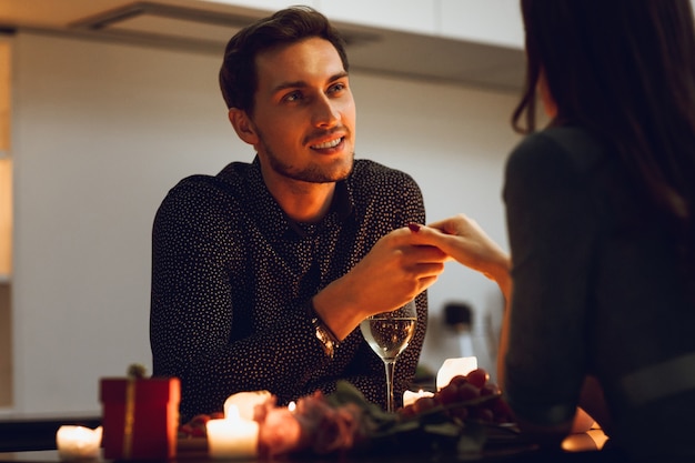 Bella coppia appassionata avente una romantica cena a lume di candela a casa, uomo che bacia la mano