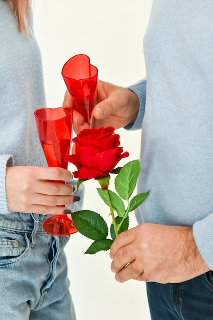 Bella coppia che celebra il loro amore, con in mano due bicchieri e una rosa rossa. Copia spazio