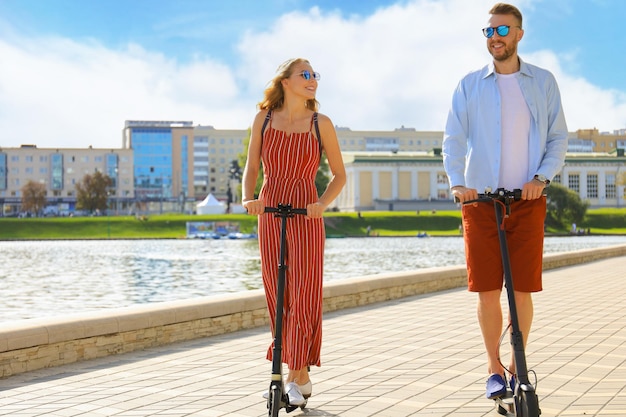 Bella coppia che si diverte a guidare uno scooter elettrico lungo il lungomare della città